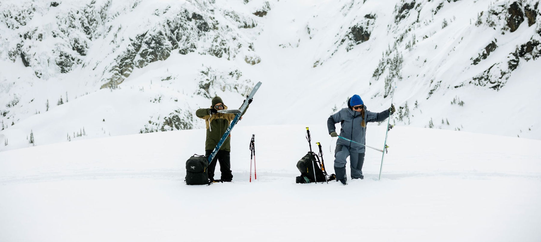 two people in snowy landscape taking climbing skins off skis