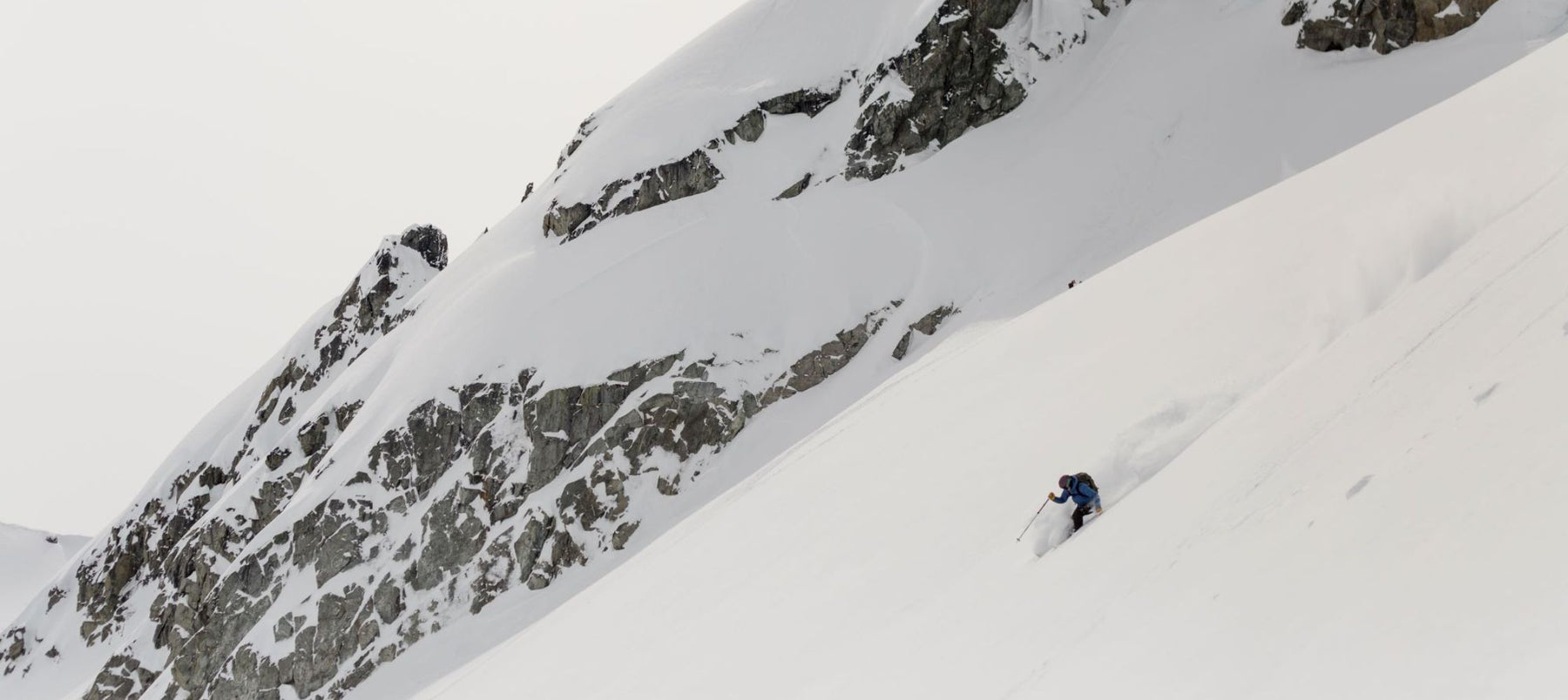 downhill skiing with mountain cliffs in background