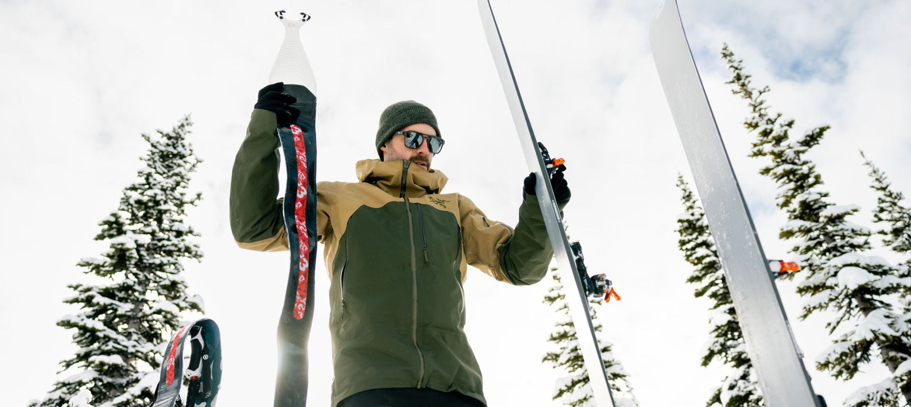 person holding up a climbing skin about to put it on a ski