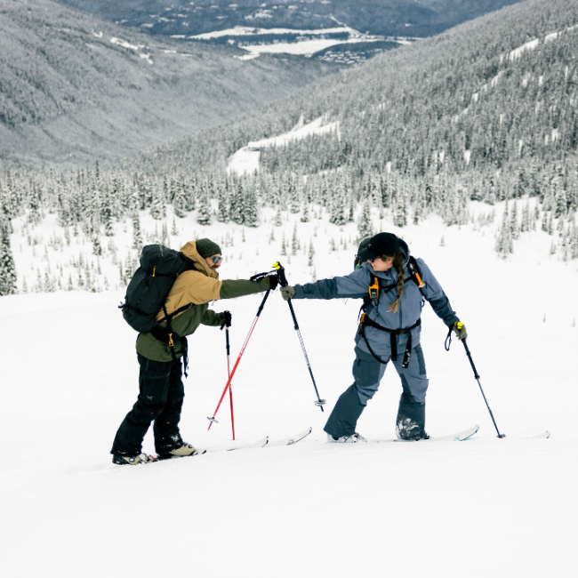 one skier looking back to tap their ski poles together with their friend behind them