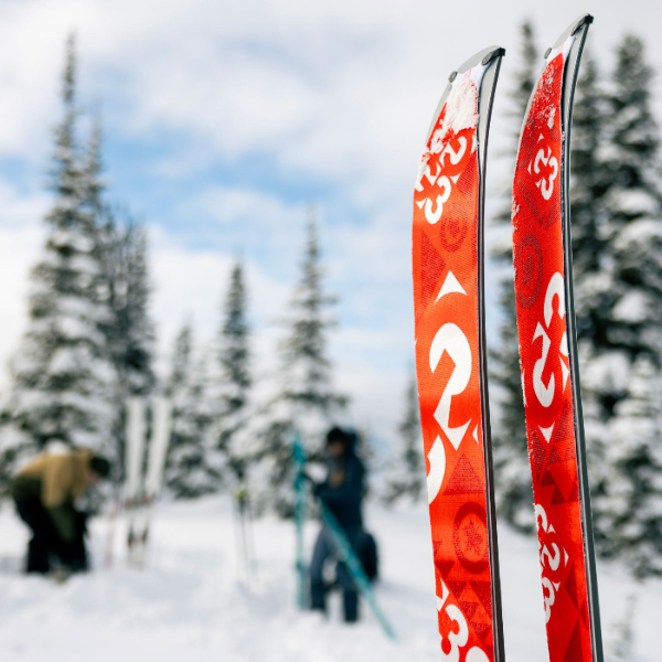 climbing skins on skis in the foreground and two people in the background