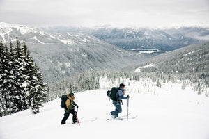 two skiers touring across a mountain holding ski poles